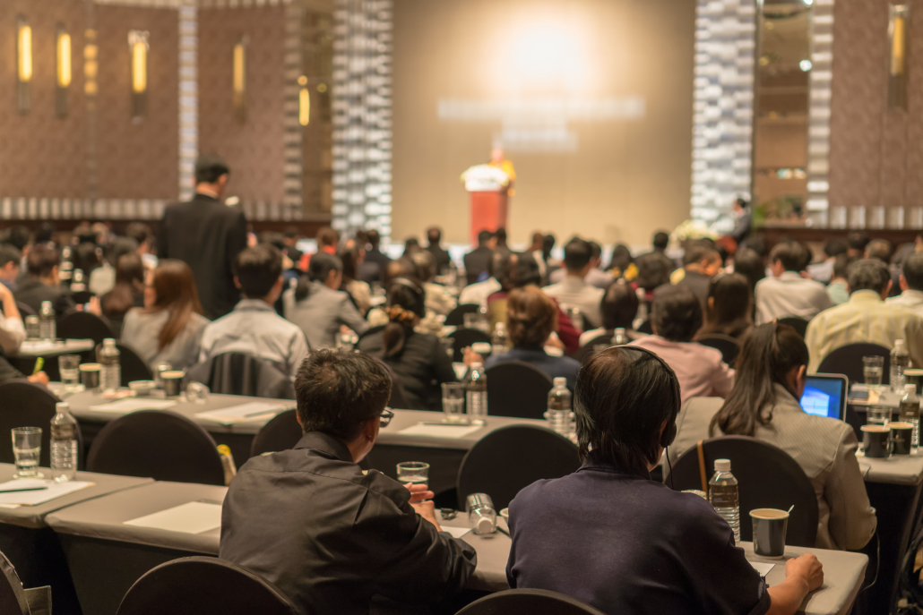 Rear view of Audience wearing and listening Speakers via Interpreter Headset on the stage in the conference hall or seminar meeting, business and education about investment concept